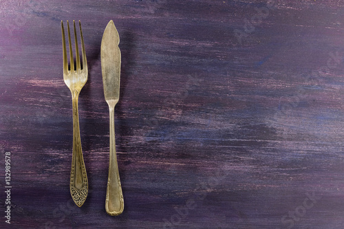 Vintage fork and knife on purple with copyspace