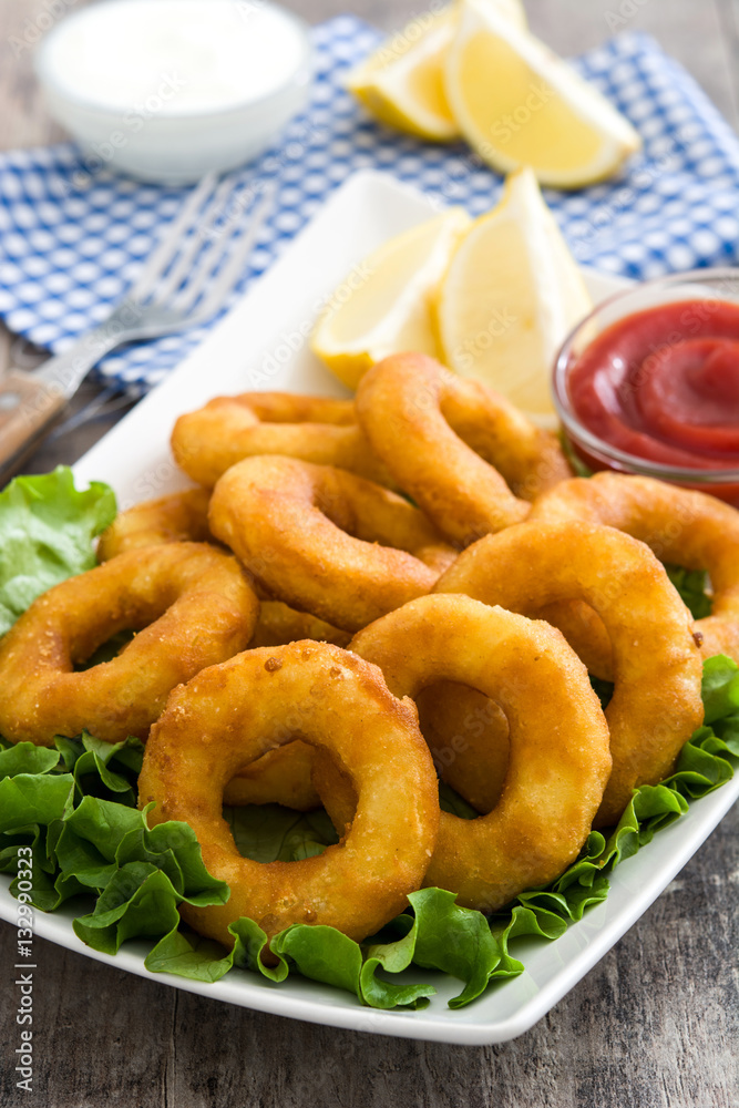 Fried calamari rings with lettuce and ketchup on wooden background
Fried calamari rings with lettuce and ketchup on wooden background