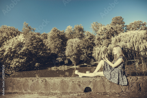 Woman sitting in park, relaxing and using phone