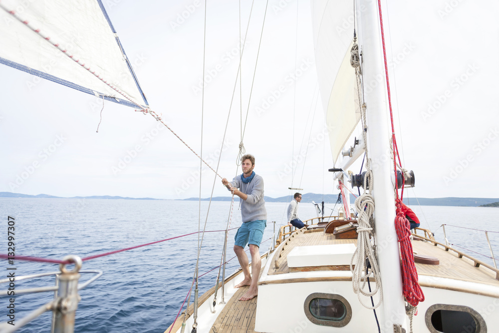 Man pulling on rope on sailboat