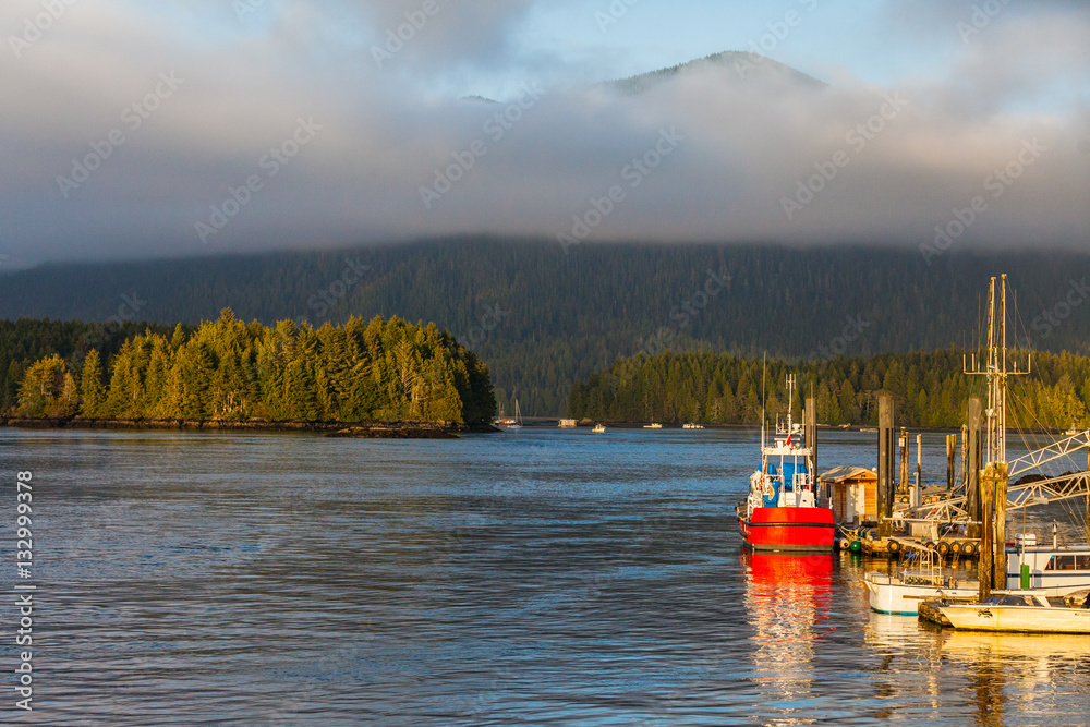 Red Coast Guard boat docked in Tofino at sunset with misty mountains in background