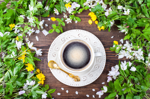 Coffee cup and spring flowers on rustic wooden background. Springtime. Top view photo