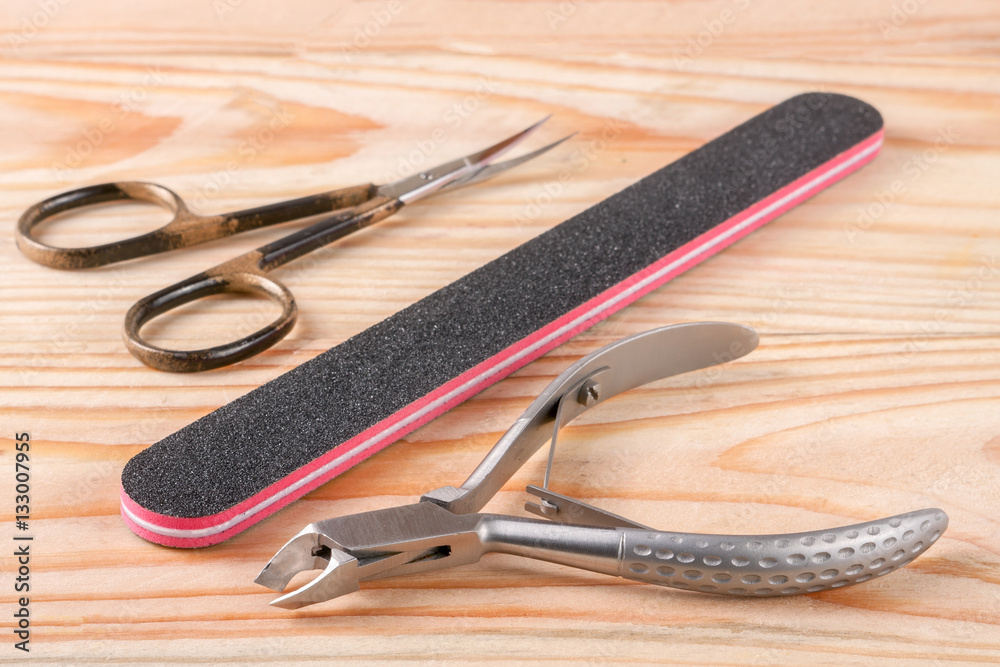 nail scissors file and clippers to remove the cuticle care products on a light wooden background