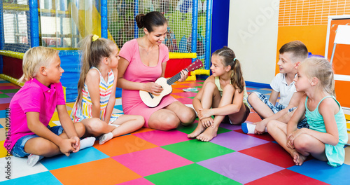 Children sitting with teacher and listening to music in class