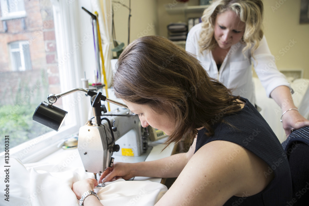 Women working at sewing machine in bridal shop Women working at sewing machine in bridal shop