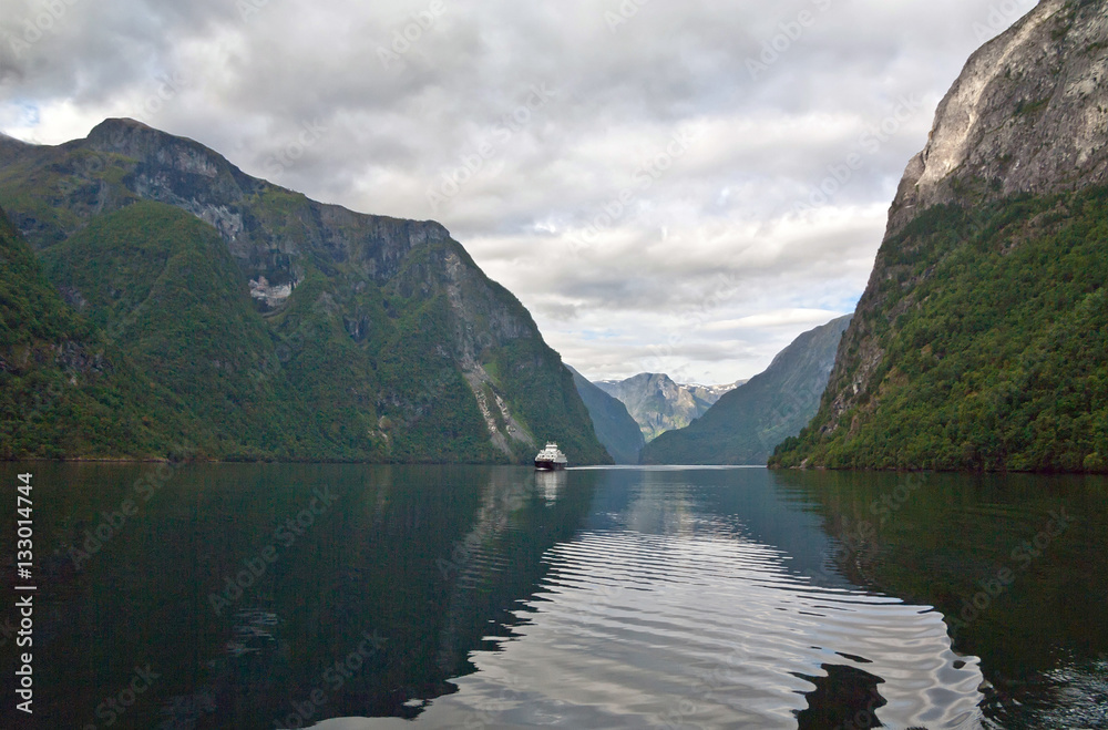The ferry sails on Norwegian fjord between the mountains. The ferry sails on Norwegian fjord between the mountains.