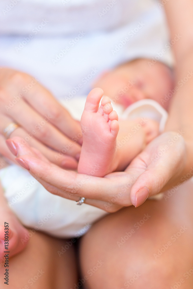 Close-up of legs, handles child. Happy mother kissing the feet, hands, fingers, the nose of the child. Gentle photo mom and baby.