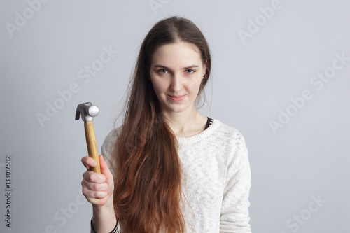 Girl holding a hammer in his hand. Independent woman repairing the house