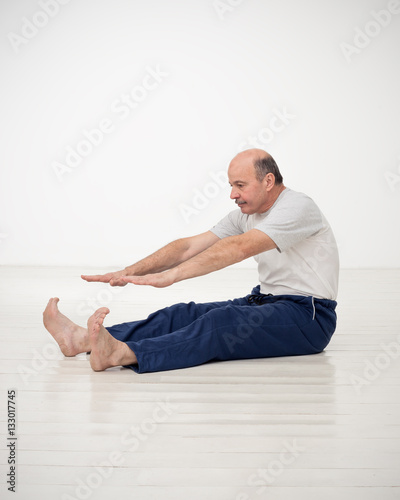 Elderly man practicing yoga or fitness. Positive mood on sports activities