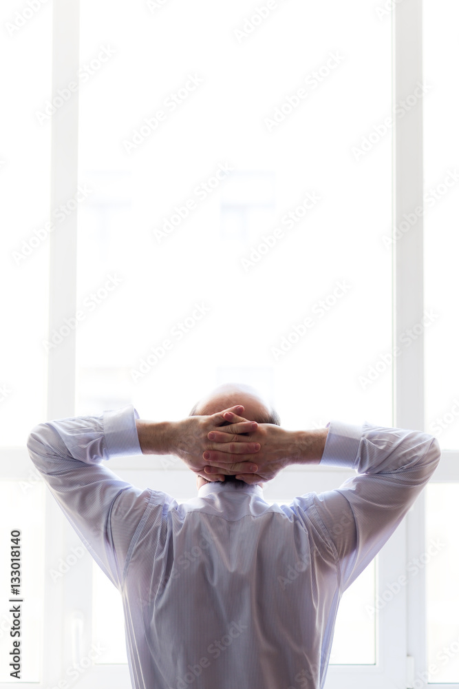 Man dreams of the future. Businessman in white shirt crossing hand on head Man dreams of the future. Businessman in white shirt crossing hand on head