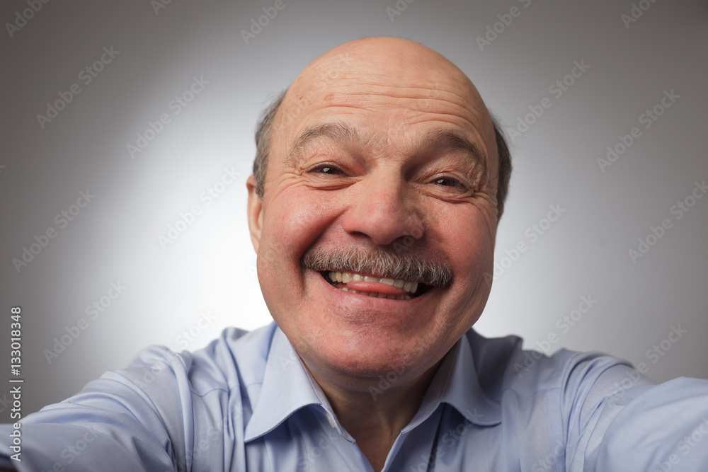 Fototapeta premium Elderly man doing selfie and shows his tongue. Fooling around