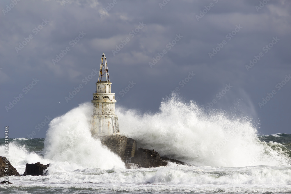 Lighthouse over waves in a stormy sea in the sunlight