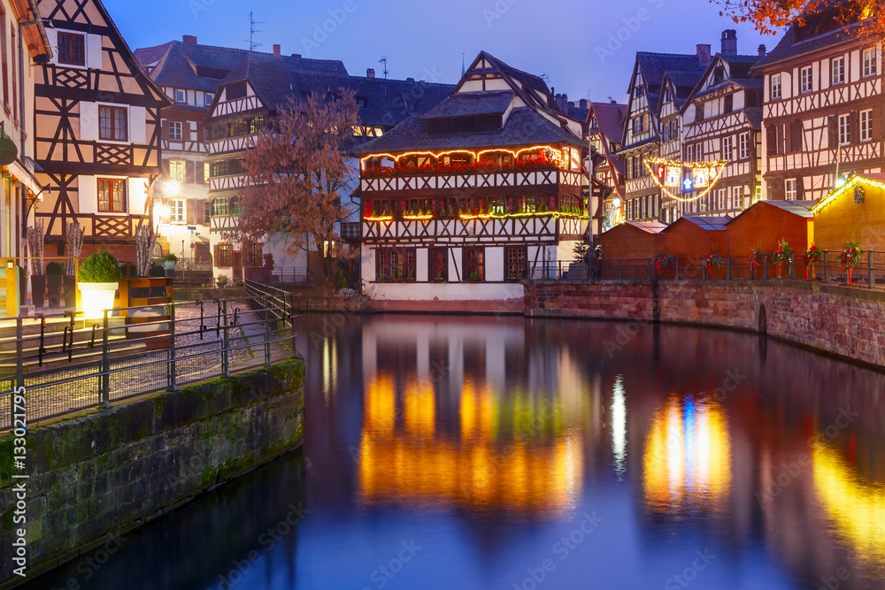 Traditional Alsatian half-timbered houses with mirror reflections in Petite France during twilight blue hour, Strasbourg, Alsace, France