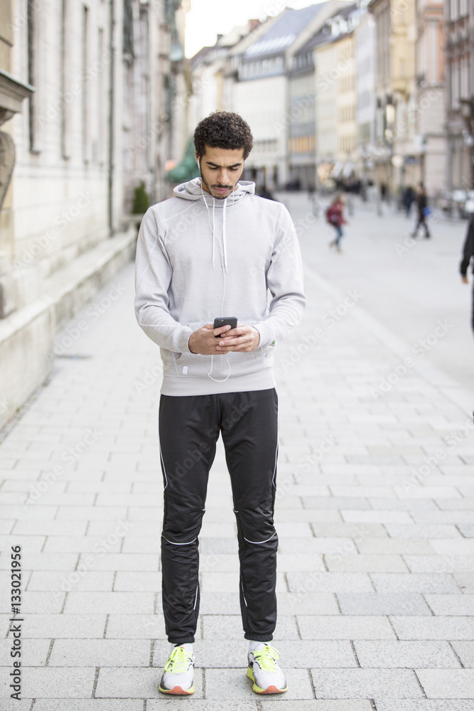 Man in sports clothing using smart phone in city Man in sports clothing using smart phone in city