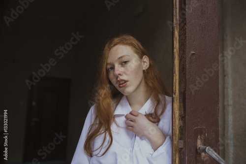 Pretty redhead model with freckles near the wooden door
