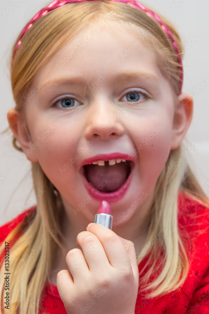 beautiful young school age girl putting on pink lipstick beautiful young school age girl putting on pink lipstick