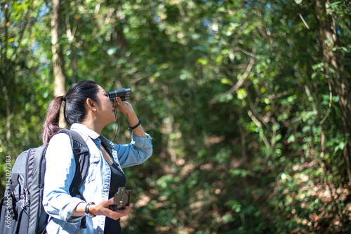 Traveler woman look binoculars on the forest, background forest Thailand, select and soft focus