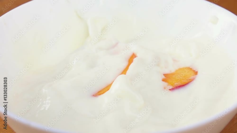 Slices of juicy peaches falling into the cream Slices of juicy peaches falling into the cream
