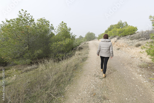 Woman passing by a dirt road © FRANCISGONSA