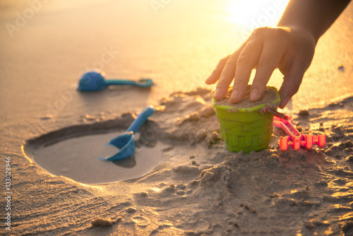 building castle on beach with toy in sunset