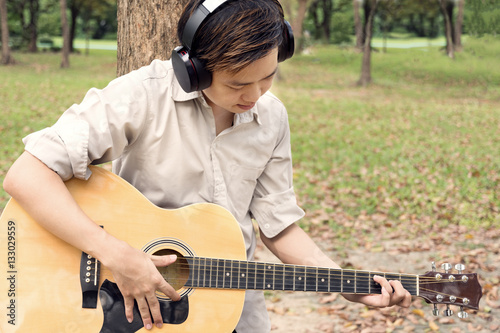 close up man is playing guitar while relaxing in public park