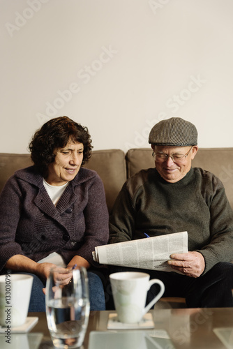 Elderly couple reading a newspaper.