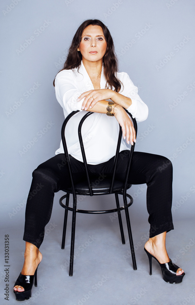 pretty brunette confident mature woman sitting on chair in studi Stock ...