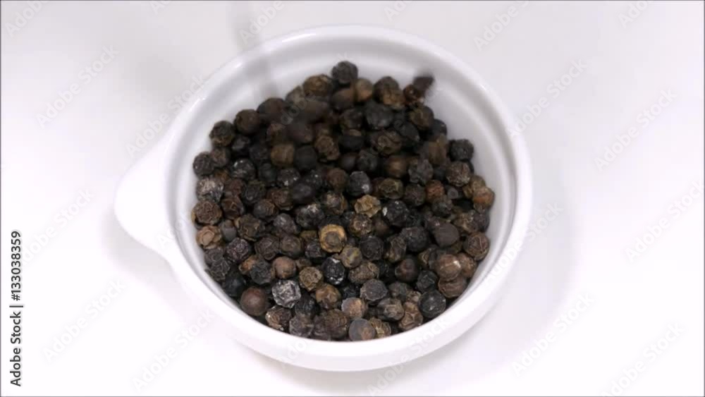 Black peppercorn dropped into a white cup. Black peppercorn dropped into a white cup.
