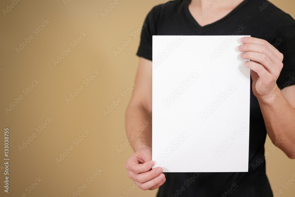 Man in black t shirt holding blank white A4 paper. Leaflet prese Man in black t shirt holding blank white A4 paper. Leaflet prese