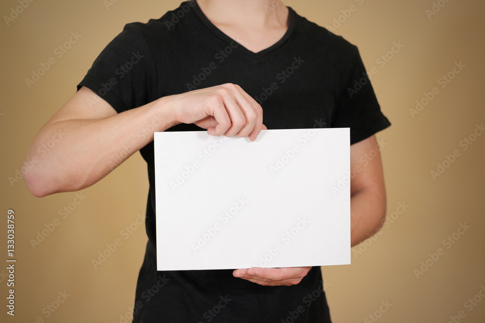 Man in black t shirt holding blank white A4 paper. Leaflet prese Man in black t shirt holding blank white A4 paper. Leaflet prese