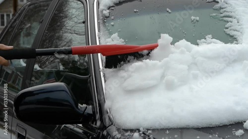 Person scrapes car windshield from snow after snow blizzard
