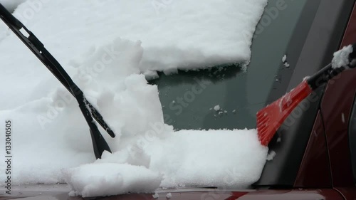 Person scrapes car windshield from snow after snow blizzard