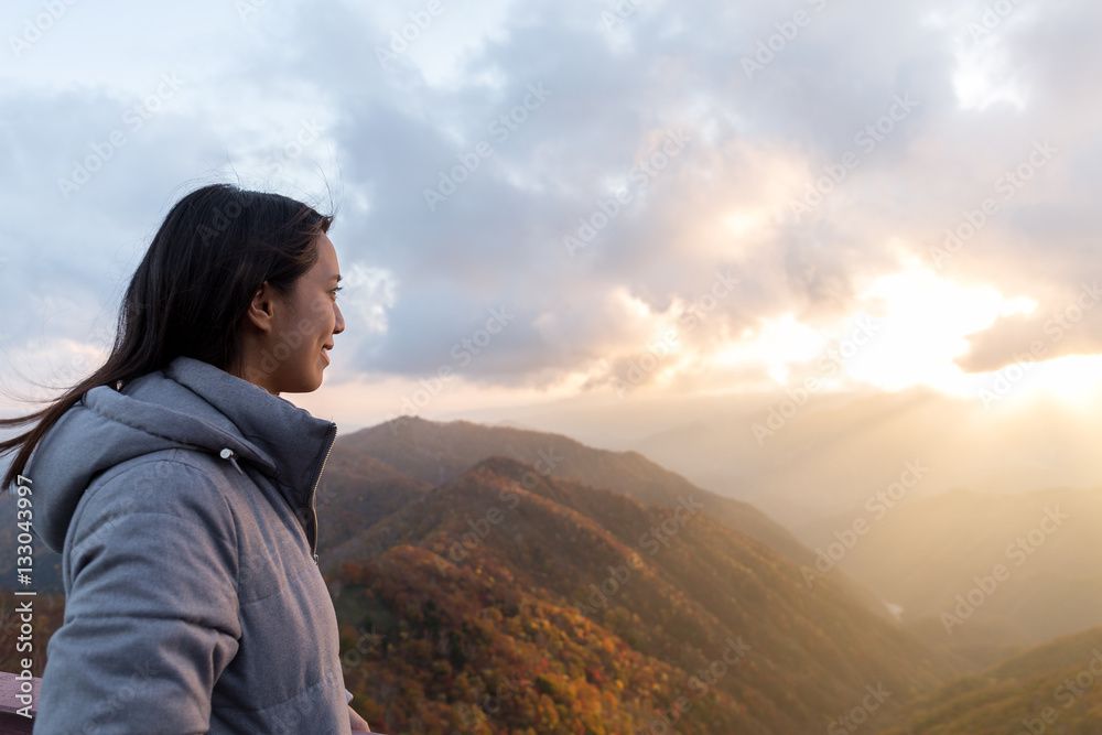Naklejka premium Woman looking at sunset on mountain