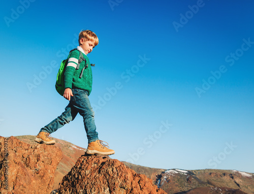little boy with backpack hiking in scenic mountains
