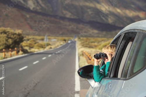 Fototapeta Naklejka Na Ścianę i Meble -  little boy looking through binoculars while travel by car on road