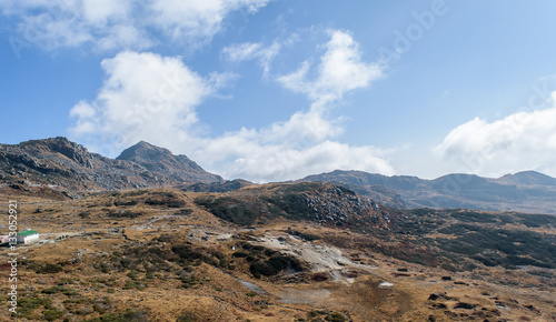 A hilltop view of mountains and blue sky with clouds.