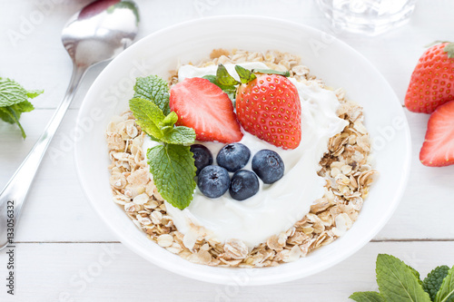 Morning healthy breakfast with muesli and berries on the white background. Side view