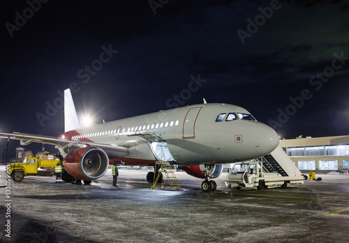 Ground handling passenger airplane at night winter airport