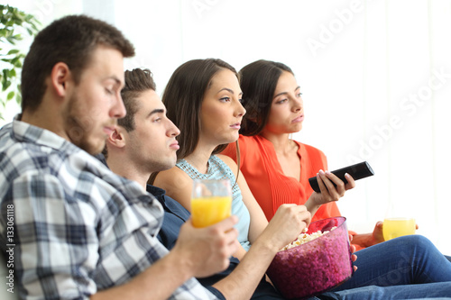 Bored group of friends watching tv at home