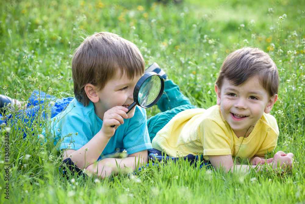 Two boys brothers with magnifying glass outdoors. Two boys brothers with magnifying glass outdoors.