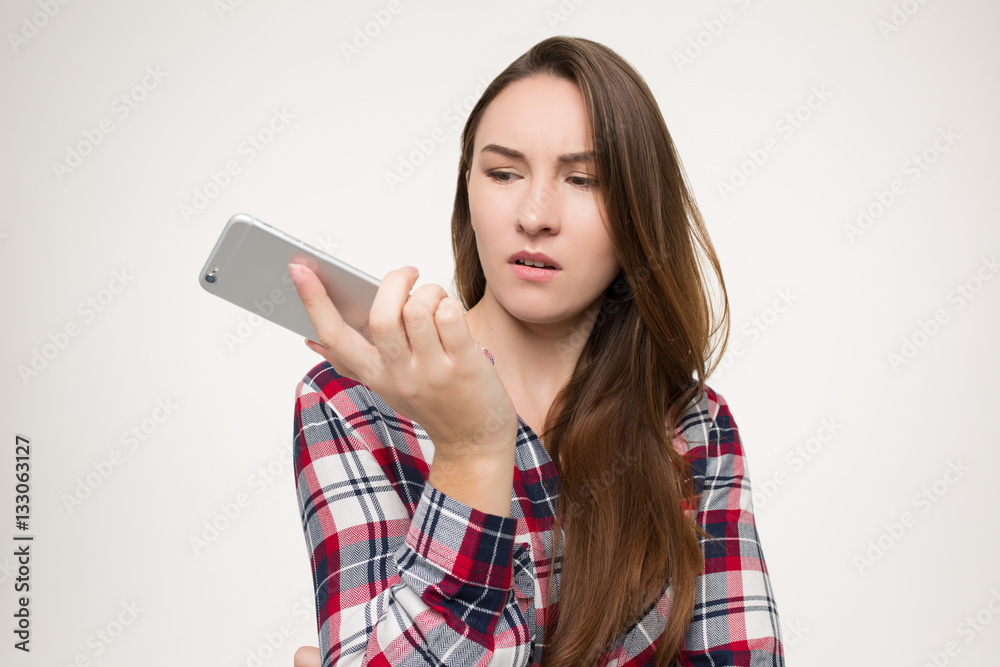 girl looks in disgust at the phone in his hand girl looks in disgust at the phone in his hand