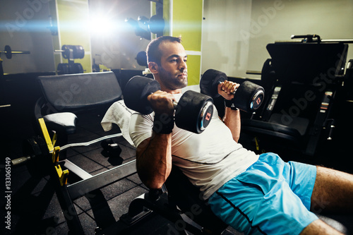 handsome bodybuilder pumping up hands in gym