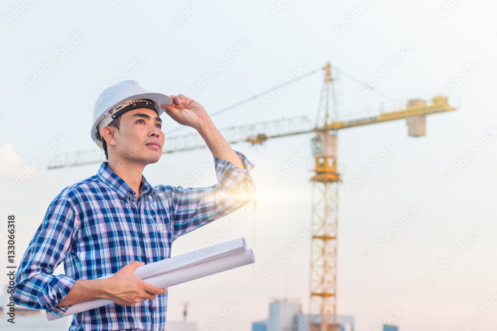 The architect wear white safety helmet and hold the blueprint wi The architect wear white safety helmet and hold the blueprint wi