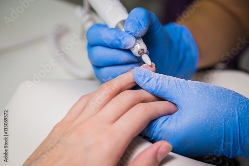 The master uses an electric machine to remove the nail polish