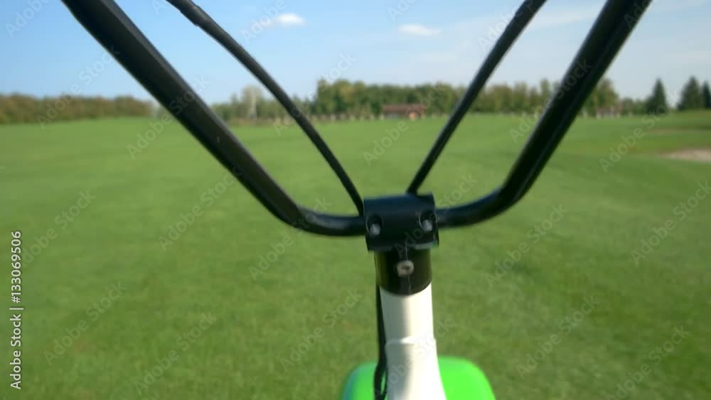 Handlebars and grass background. Electric scooter moving. Testing the new eco transport. Handlebars and grass background. Electric scooter moving. Testing the new eco transport.