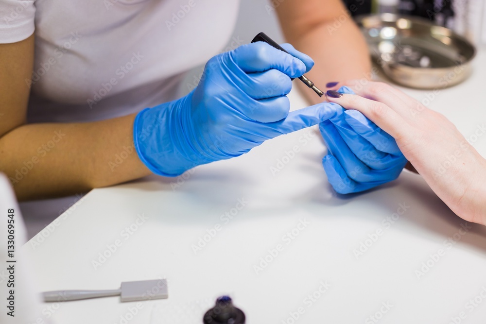 Professional beautician applying nail polish to female nail Professional beautician applying nail polish to female nail