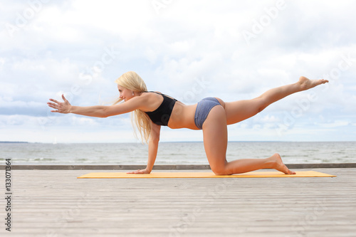 Woman doing yoga at the sea