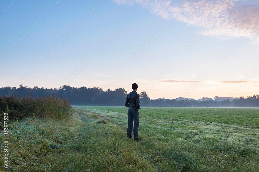 Young man standing in misty meadow on cold morning. Noordijkerve