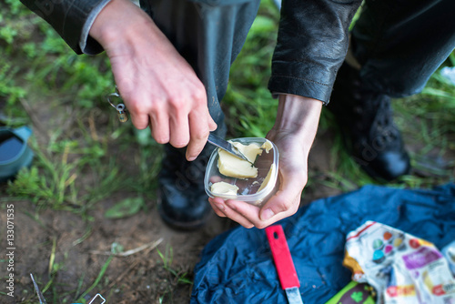 Male hand with knife grabbing butter out of container during hik