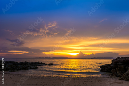 beautiful twilight sunset sky over sea with rocks in foreground